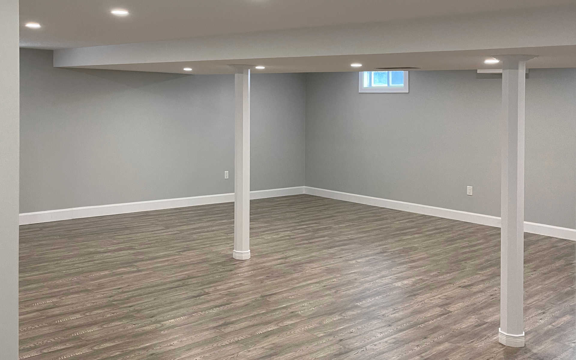 Grayish beige luxury vinyl engineered wood, or solid hardwood flooring in a modern rec room or newly finished basement. A London Ontario interiors renovation / flooring project by Brothers Construction.