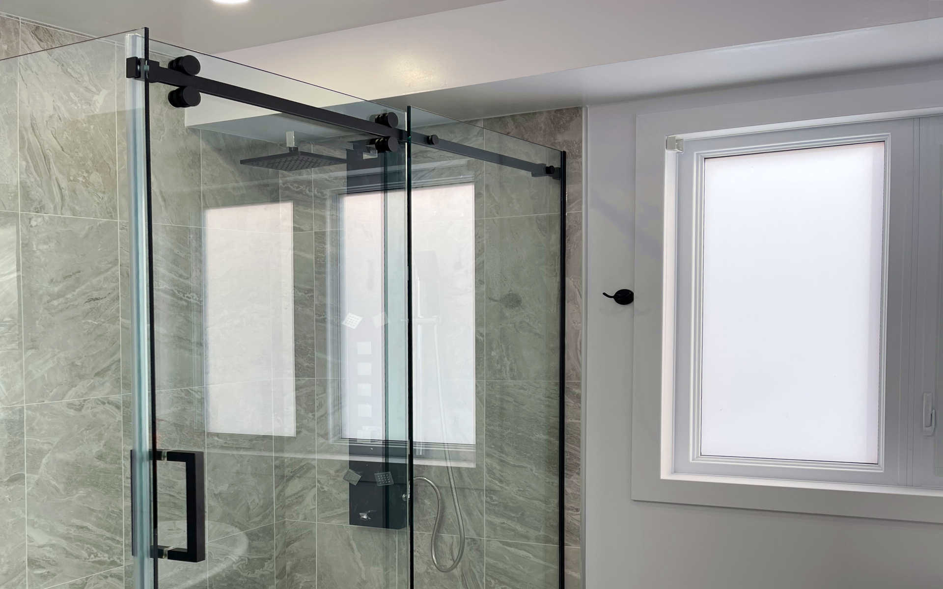 Glass shower bathroom. A modern bathroom design and renovation, glass shower enclosure, tempered glass, handles and mounting hardware, ceramic tiles, tile flooring, faux marble or stone tile flooring and walls. A London Ontario bathroom and shower renovation project by Brothers Construction 3 Inc.