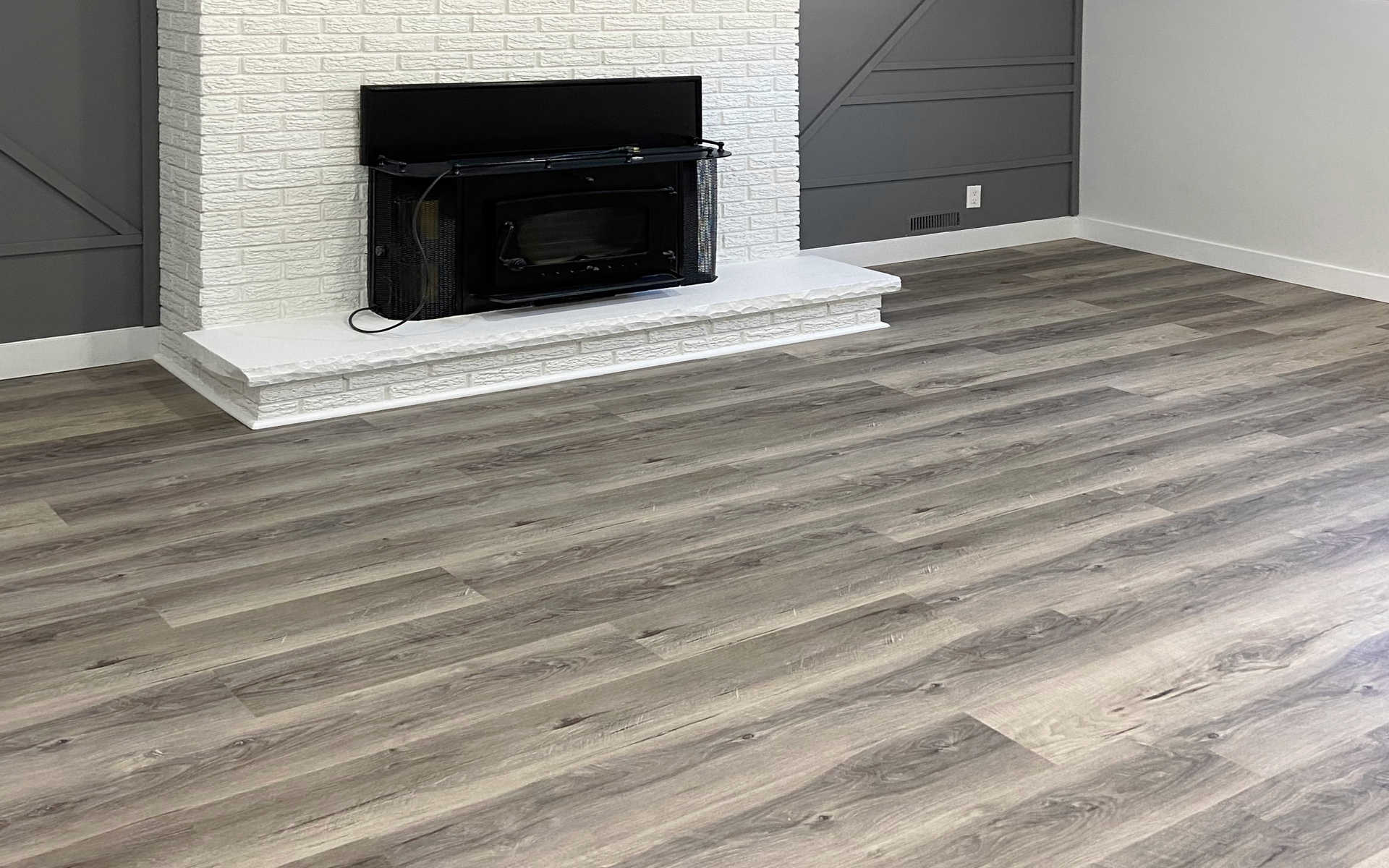 A modern living room, basement or recroom with a fireplace and hardwood flooring or luxury vinyl flooring. A London Ontario interiors renovation project by Brothers Construction 3, home renovation contractors in London.