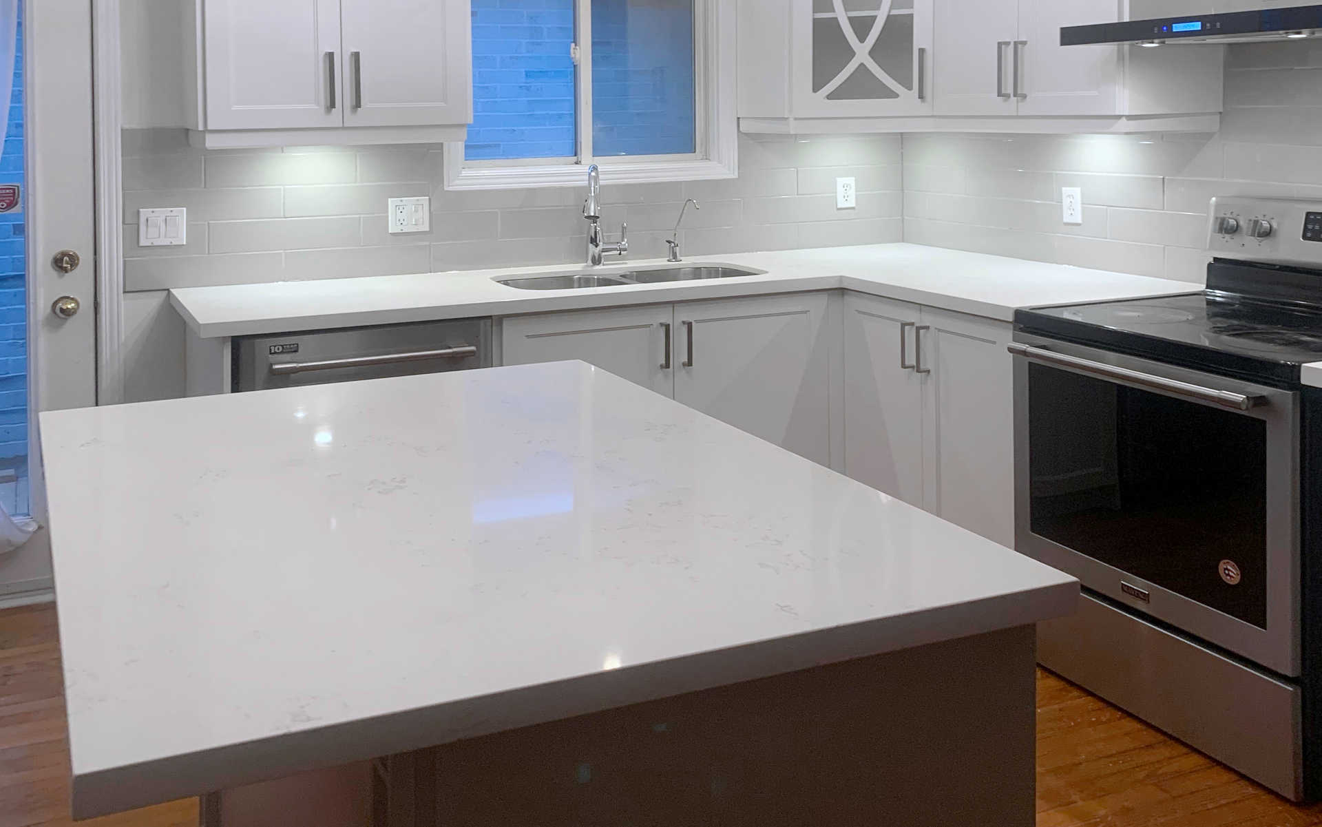 A modern kitchen design and renovation, cupboards, faux stone or stone counter tops, kitchen island, flooring, painting and more. A London Ontario home and kitchen renovation project by Brothers Construction 3 Inc.